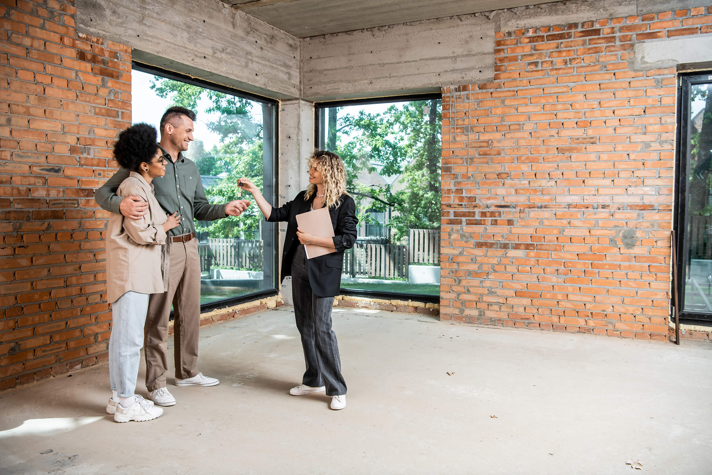 real estate agent giving keys to interracial couple